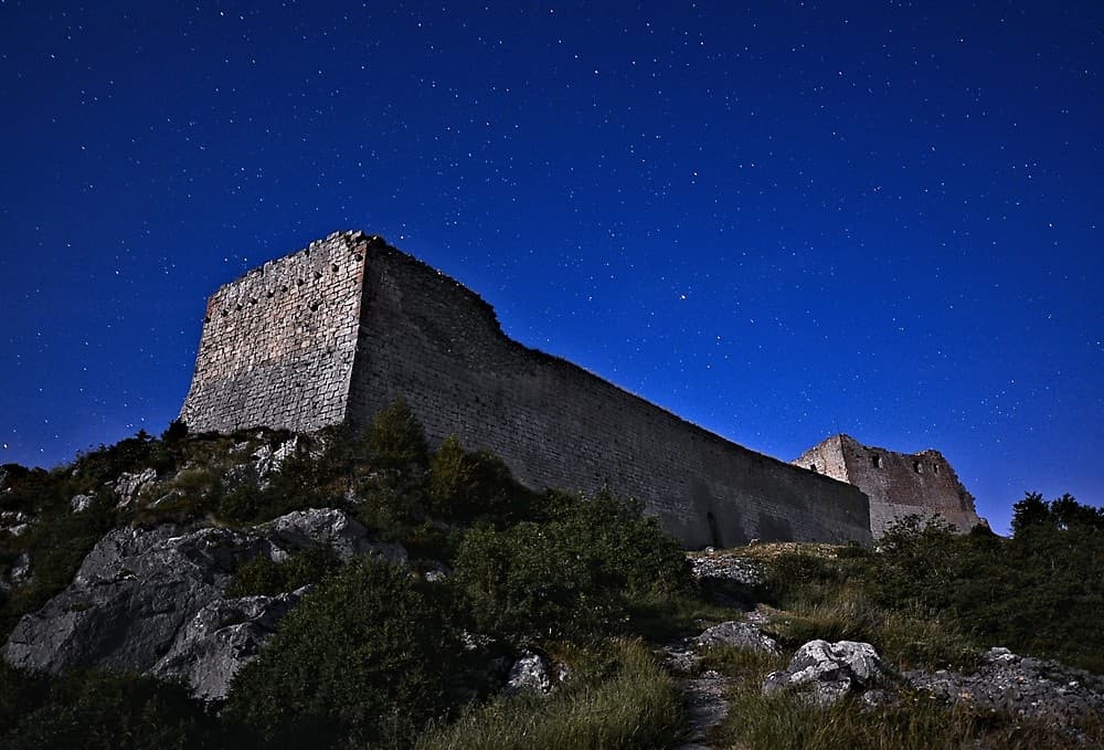 Le château de Montségur, refuge des derniers cathares, sous les étoiles, éclairé par la pleine lune (Ariège ; photographie nocturne : Philippe Contal)