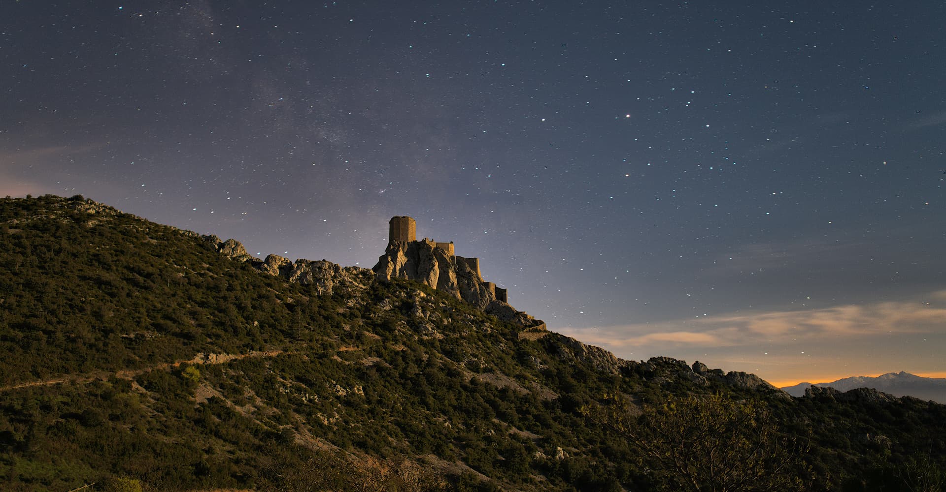 Photographie nocturne (19 avril 2016 à 4 h 39) avec l’éclairage naturel de la lune (91 %). Le fin voile lumineux qui semble s'échapper de la silhouette de Quéribus est la Voie Lactée (9ᵉ place au concours Wiki Loves Monuments 2017 sur 245 000 images) | Philippe Contal