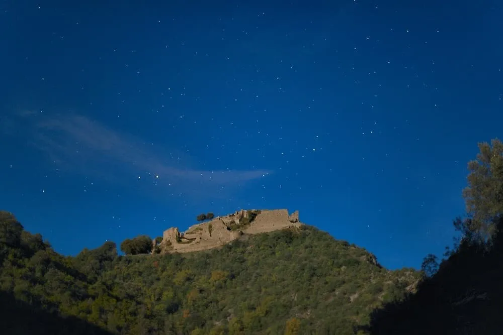 Le château de Termes sour les étoiles, éclairé par la pleine lune, peu avant l'éclipse totale lunaire (Corbières, Aude, Pays cathare ; photographie nocturne : Philippe Contal)
